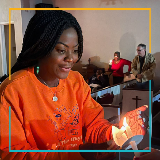 Woman lighting a candle wearing an orange shirt